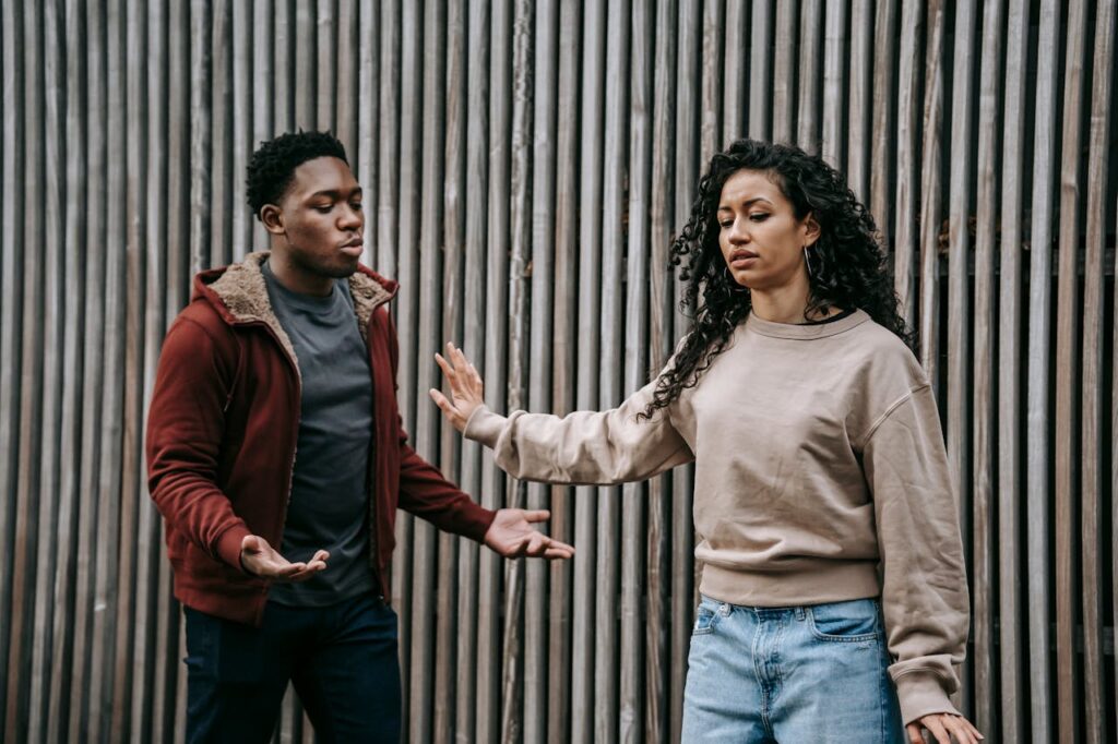 Man talking to a woman. Woman is walking away from him with her hand blocking him.